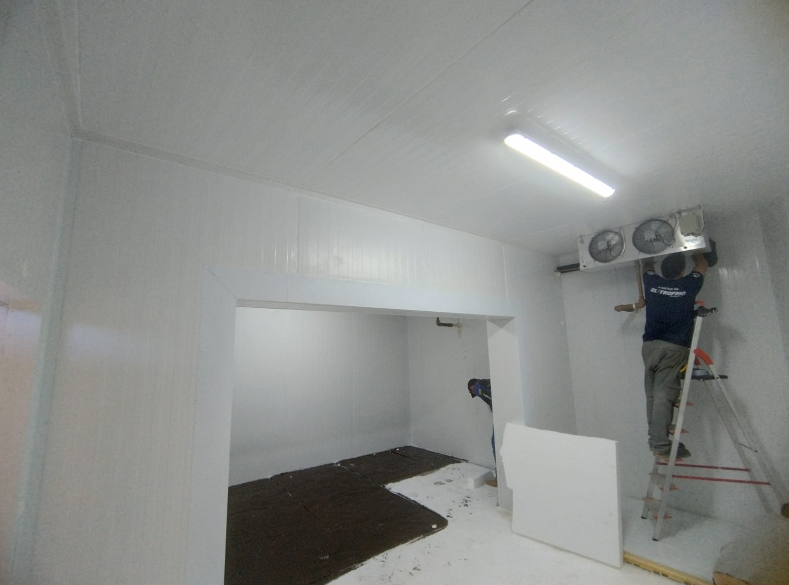 Interior de câmara fria em finalização com instalação de piso e parede